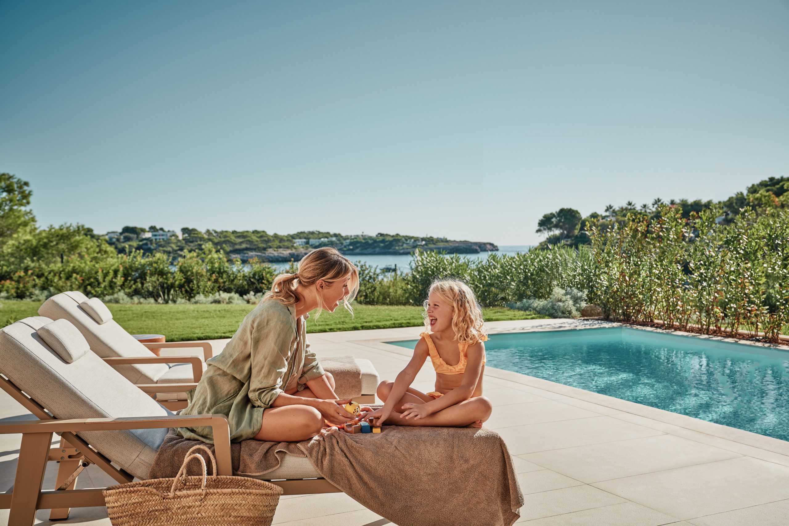 A mother and daughter sharing a moment beside a private pool at Ikos Porto Petro